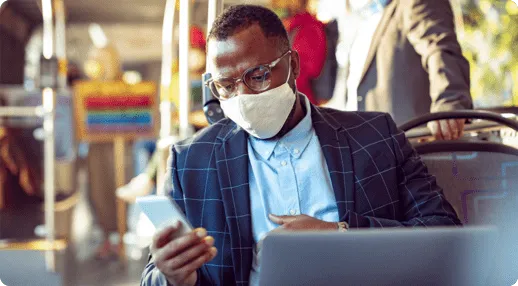 Man representing an RMS patient wearing gasses and a mask uses a cell phone and laptop